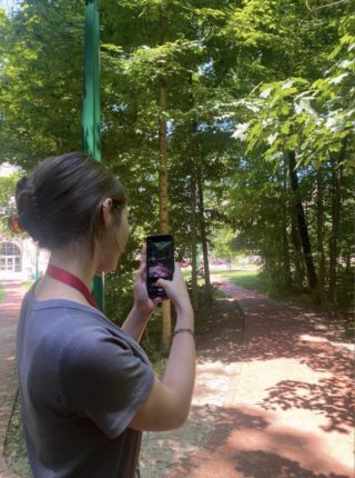 A student sits outside and takes a photo of a brick trail on IU's campus