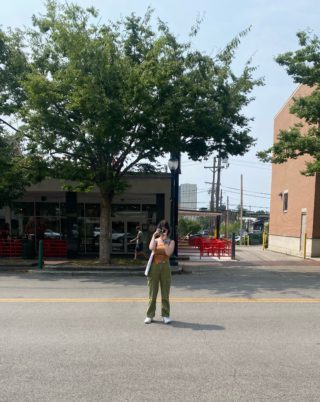 A person stands in the middle of the street and takes pictures with a camera
