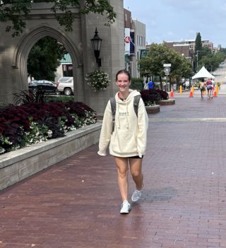 A student wears a sweatshirt as they walk through the Sample Gates on Indiana Avenue