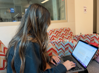 An HSJi student works on their laptop in the Franklin Hall Commons