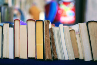 Books are lined up on a shelf with their spines facing upward