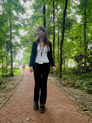 A woman walks on a path through a woodsy area.