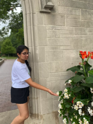 A student reaches her hand out to touch some flowers.