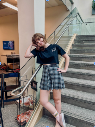 A woman leans on the glass railing of a staircase.