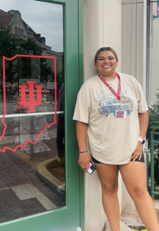 A student stands beside a door to a shop with an IU Indiana icon on it.