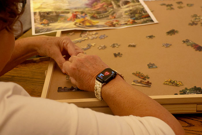 A woman with an Apple Watch works on a puzzle. 