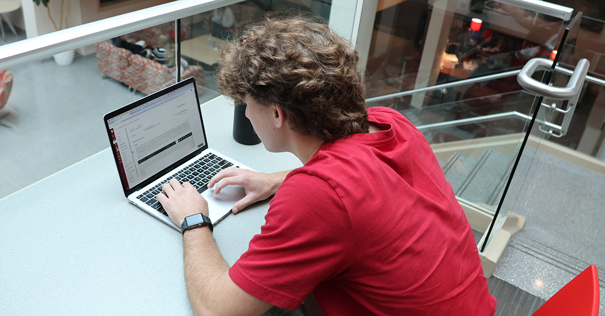 Male college student sits at desk, completing his assignment.