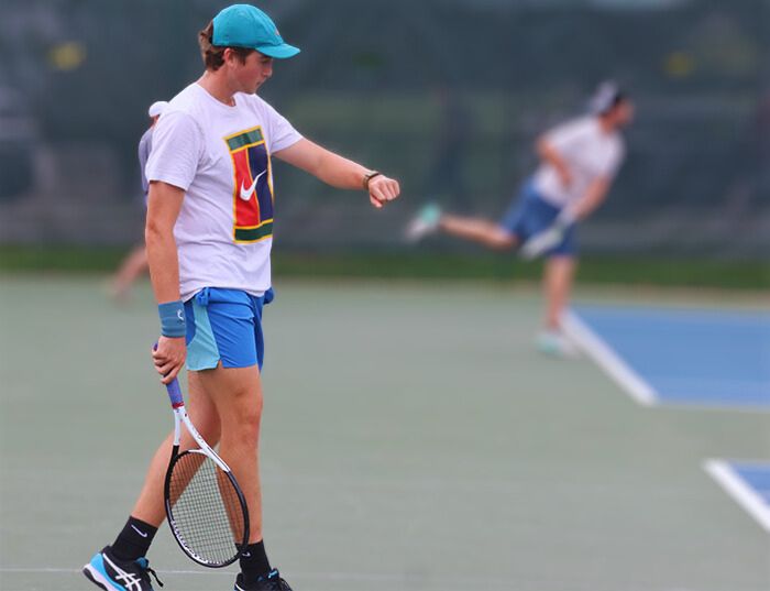 IU Tennis player at team practice using his apple watch.