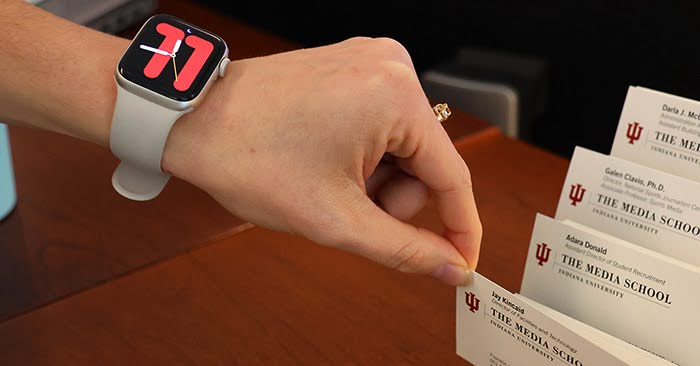 College student flexes her stylish Apple Watch as she flips through some papers. 