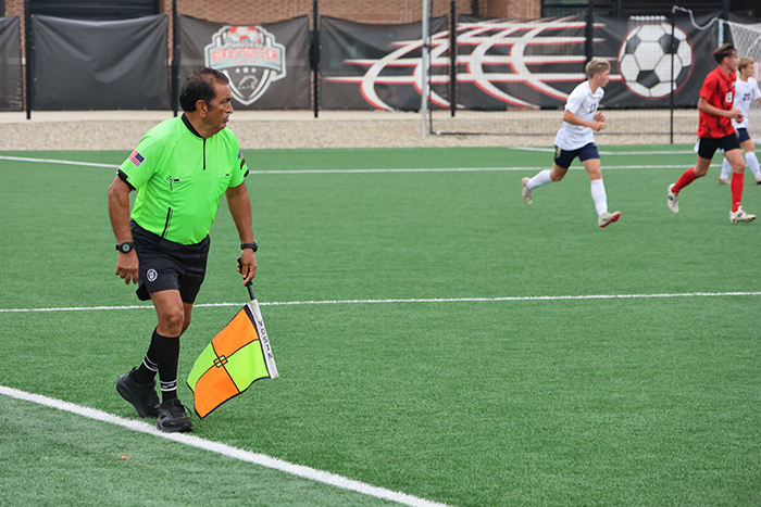 Soccer referee holds flag while watching the game.