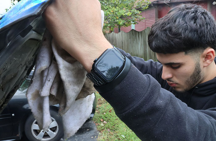 Young man wearing his Apple Watch and working on his car.