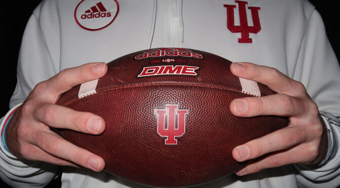 Athlete in IU gear holding IU football