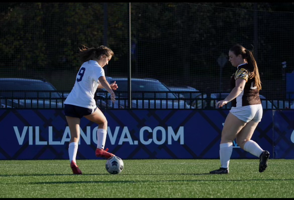 two women on soccer field playing with a soccer ball