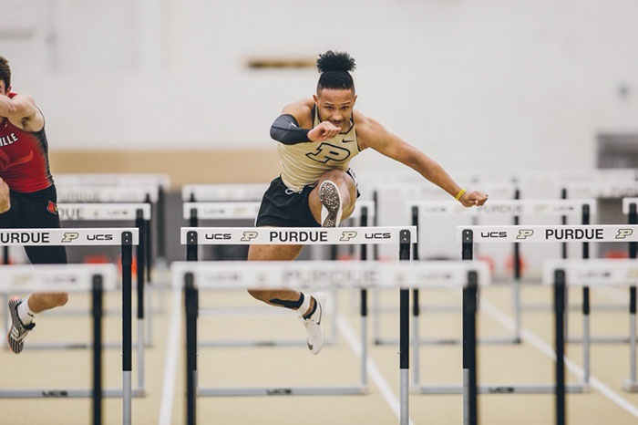 Bruce Stephens leaps over a hurdle in the Purdue gym.