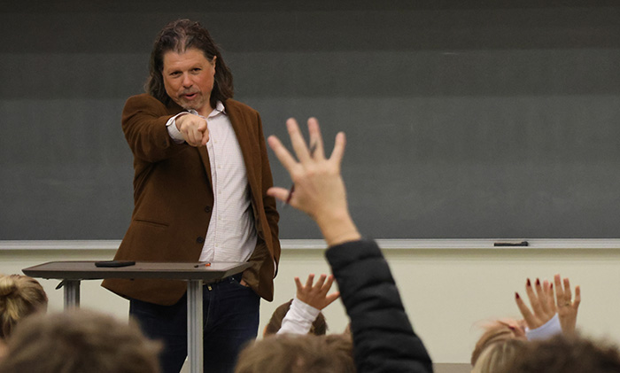 Galen Clavio points to a waving hand in a crowd of Junior reporters ready to ask him about NIL