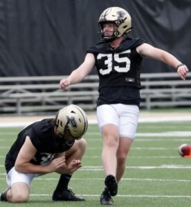 Football player in Purdue University Uniform practicing kicking