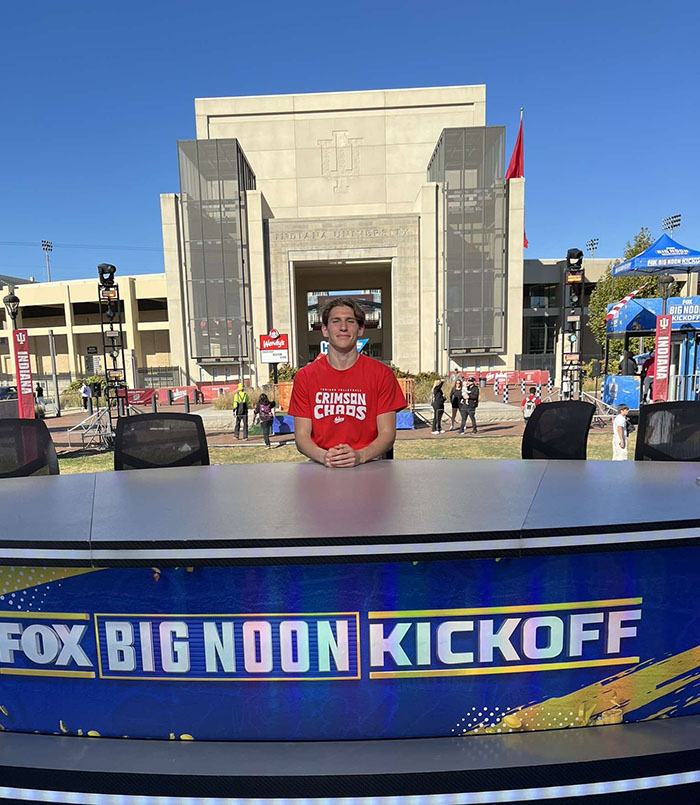 Noah Szik, a former Emory swimmer, smiles for a photo behind the FOX Big Noon Kickoff table. Photo courtesy of Noah Szik.