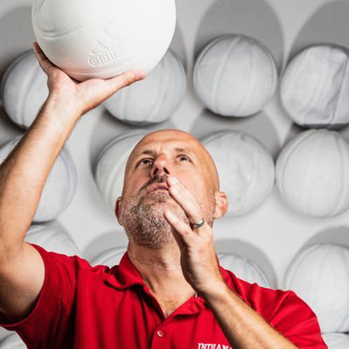 Jeremy Gray, the Senior Associate Athletic Director at Indiana University, holds up a basketball painted white above his head. 