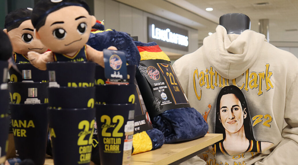 An end cap is featured showing plushies of Indiana Fever basketball player Caitlin Clark and a Caitlin Clark hoodie.