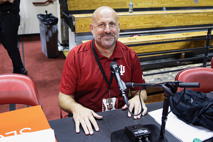 Jeremy Gray, Director of the Cuban Center, sits at a desk with a mic and rig in preparation for Hoosier Hysteria. 