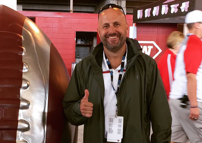 Jeremy Gray gestures a thumbs up at a football event.