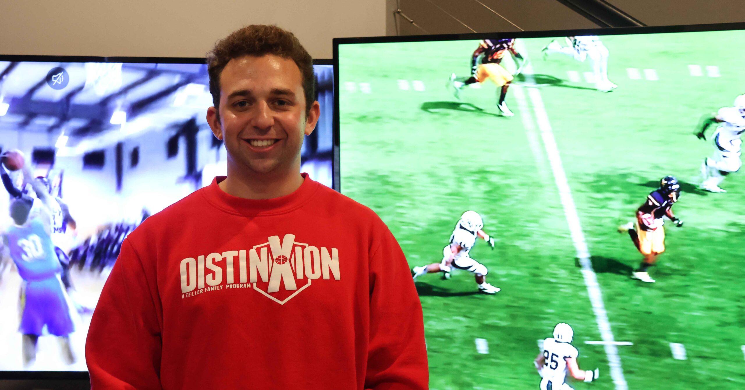 Luke Maslin stands in front of two sports games being played to show his love for the game.