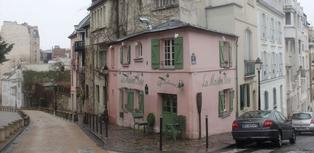 A street in Montmartre. The most immediate building is a pink cafe called "La Maison Rose Cafe & Restaurant"