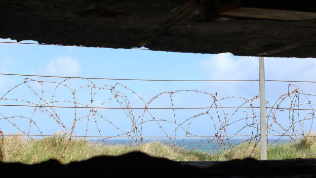 The view of Omaha Beach from behind barbed wire of a bunker