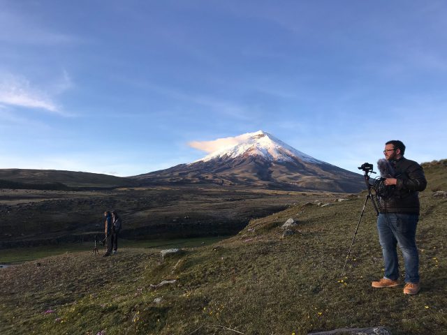 Liam O'Sullivan operates a camera in front of a mountain.