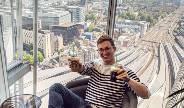 Asher Michelson poses inside The Shard with two Starbucks cups in hand.