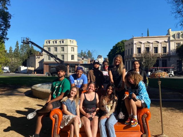 A group of students poses on the "Friends" couch in front of the fountain set in Los Angeles.
