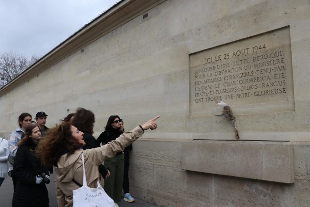 a woman points to a memorial in Paris