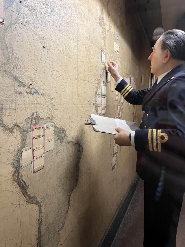 an exhibit in the Churchill War Rooms shows a representation of Churchill looking at a map holding a clipboard