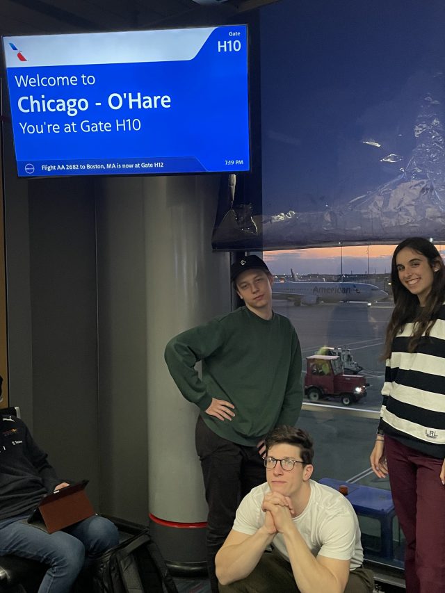three students gather around a gate sign in Chicago O'Hare Airport on their way home from London